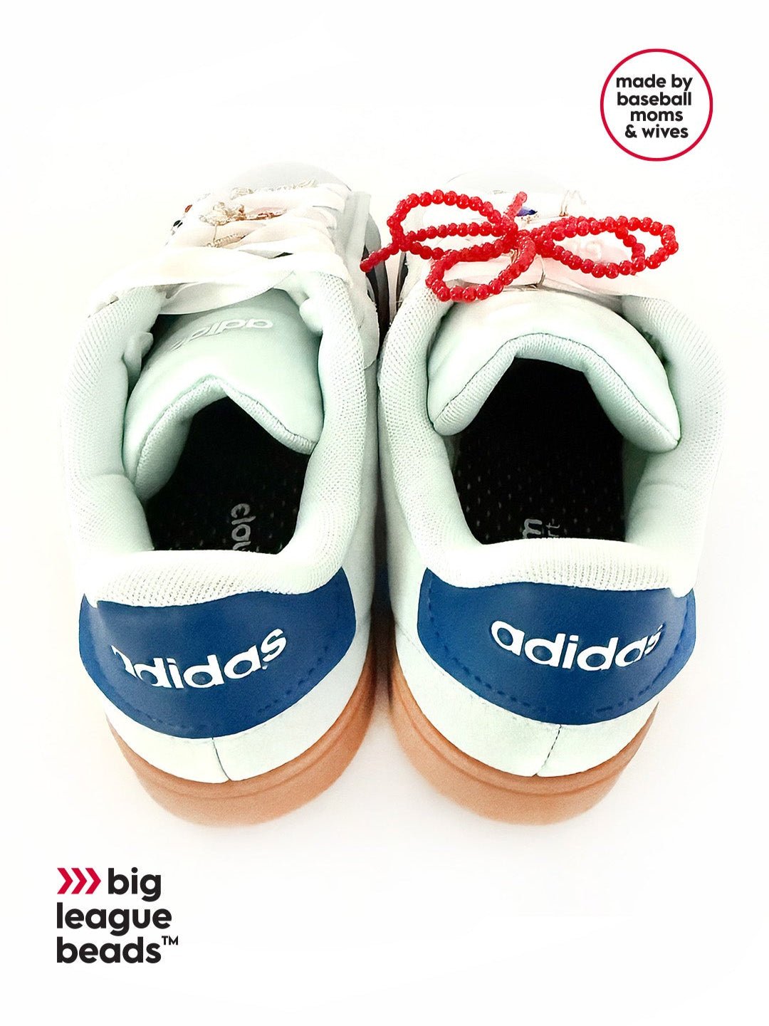 Pair of white Adidas sneakers with red beads on a white background